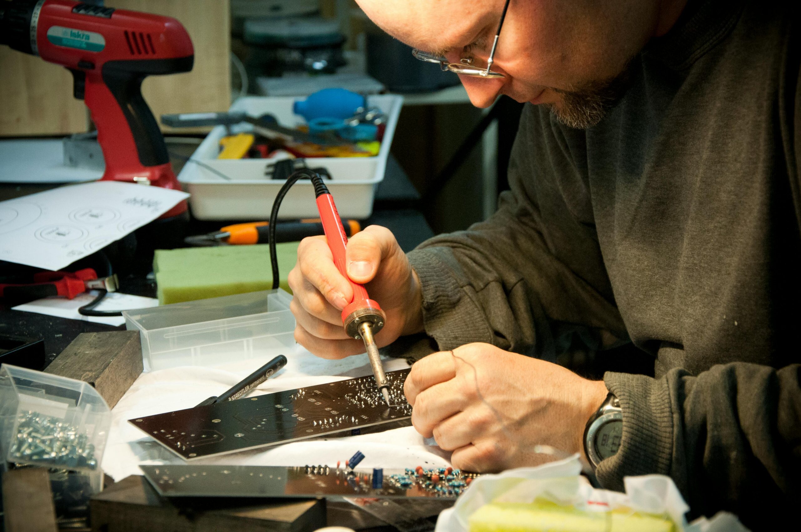 A focused technician skillfully soldering a circuit board at a workbench, highlighting precision and craftsmanship.